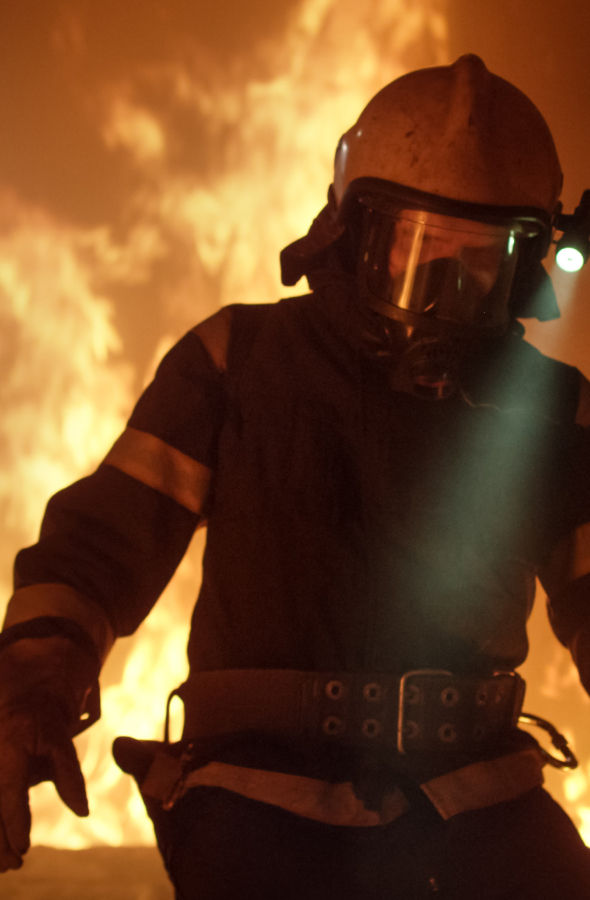 Firefighter in front emerging from the flames wearing Karapace® fabric